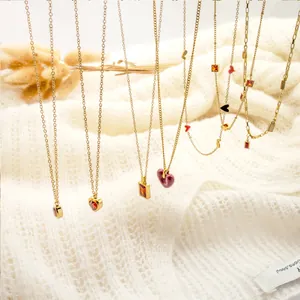 Detail of layered gold necklaces with heart and gemstone pendants on a knit sweater
