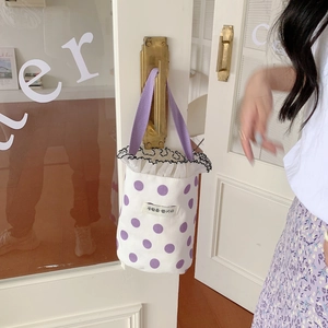 Detail of canvas mini bucket bag featuring purple polka dots and ruffled lace trim