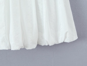 Close-up of white dress showing intricate floral lace embroidery and eyelet details