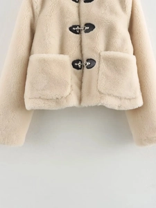 Détail de veste en polaire beige avec boucles en similicuir noir et attaches métalliques