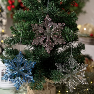 Clear acrylic snowflake pendants in pink and blue hanging on a Christmas tree
