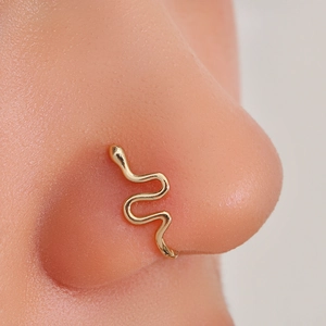 Macro shot of a golden snake-shaped non-piercing nose ring clip on a female nose