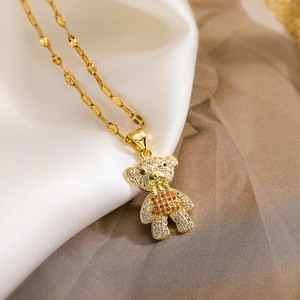 Macro shot of gold-plated bear pendant with white and orange cubic zirconia on satin