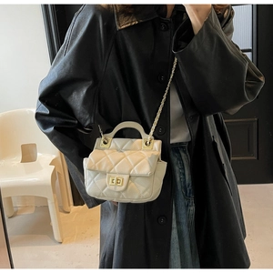 Close-up of cream quilted leather crossbody bag with gold lock and chain strap
