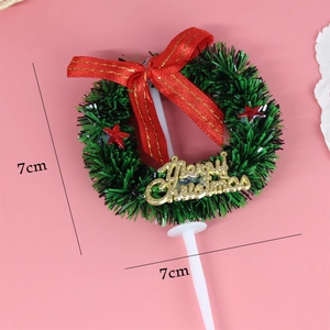 Detail view of a 7cm green tinsel wreath cake topper with red bow and Merry Christmas sign