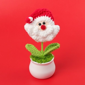 Close-up of handmade crochet Santa Claus flower in a white ceramic pot for Christmas decor