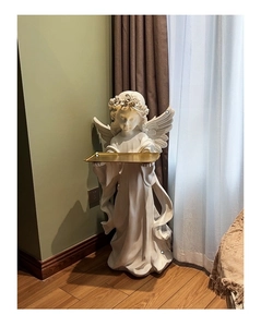Detail of angel statue holding a large gold metal tray for home decor storage