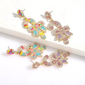 Detailed close-up of Christmas candy cane earrings with colorful rhinestones and bows
