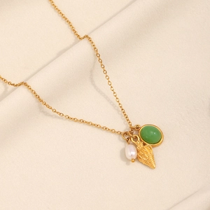 Detail of 18K gold necklace with green gemstone, white pearl and conch shell charms