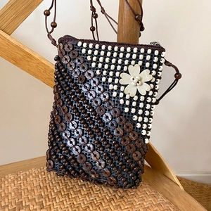Detail of bohemian coconut shell beaded crossbody bag with white flower decoration