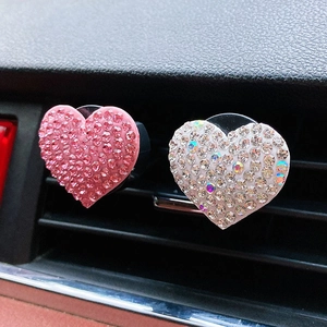 Detailed view of pink and white rhinestone heart car air vent clips installed on dashboard