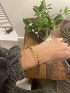 Twisted wave pattern gold bangle in 18k plated stainless steel on wrist