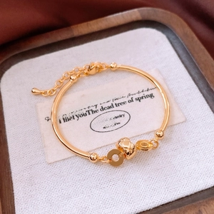 Macro detail of 18K gold-plated bamboo bracelet with quilted sphere and adjustable chain