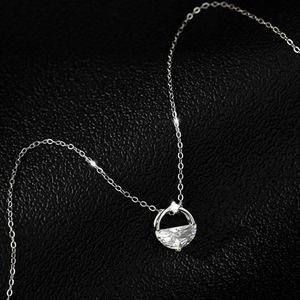 Macro view of D-shaped silver necklace pendant with faceted gemstone on black leather