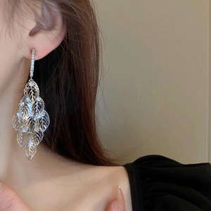 Close-up of model wearing silver long leaf tassel earrings with sparkling rhinestones