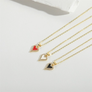 Detailed view of three minimalist gold necklaces with red, white, and black heart pendants