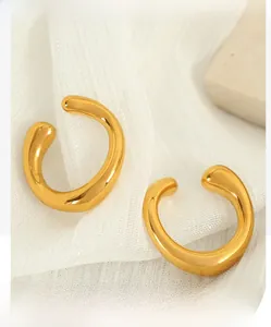 Macro shot of polished gold-tone C-shaped ear cuffs on elegant white mesh fabric