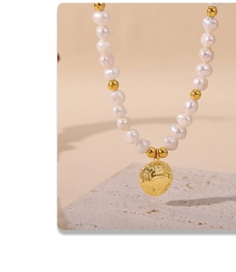 Detail of freshwater pearl necklace with gold earth relief pendant on a beige stone stand