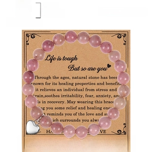 Bracelet en perles de rhodochrosite rose avec pendentif coeur sur carte kraft