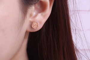 Close-up of elegant rose gold sparkling crystal ball earrings on a female model