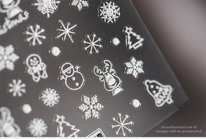 Macro shot of 5D white embossed Christmas nail stickers with snowflakes and reindeer