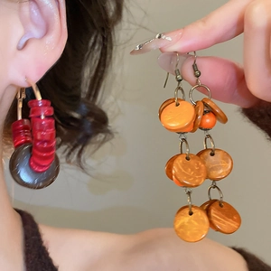 Détail de boucles d'oreilles bohèmes perles de bois rouges et couches orange vif
