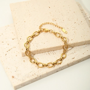 Detail of 18K gold plated chain bracelet with lobster clasp on beige stone background
