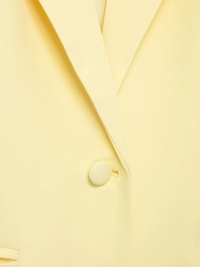 Detail shot of the light yellow blazer neckline and elegant fabric-covered button