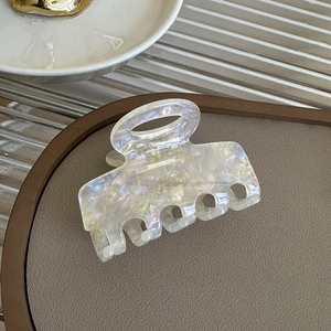Detailed macro shot of a pearlescent white hair claw clip with golden Barrette France text