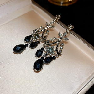 Detailed close-up of vintage palace-style silver earrings with black crystal teardrops
