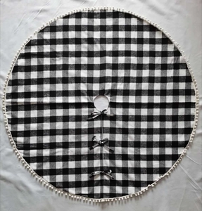 Detail der schwarz-weiß karierten Weihnachtsbaumdecke mit weißen Pompons und Schleifen