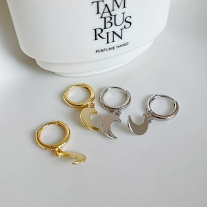 Detail of silver and gold crescent moon dangle earrings on a clean white surface