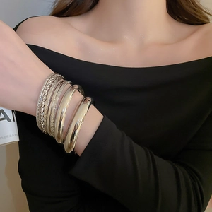 Détails de bracelets dorés empilés avec des textures lisses, rayées et torsadées