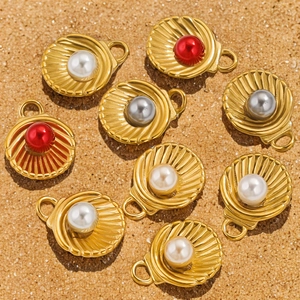 Pendentifs en forme de coquillage en acier avec perles sur fond de sable naturel