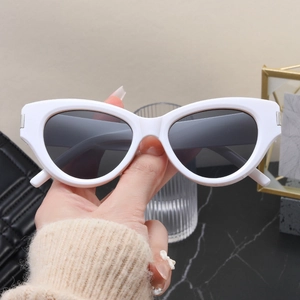 Close-up of white cat-eye sunglasses featuring silver metal hinge and dark lenses