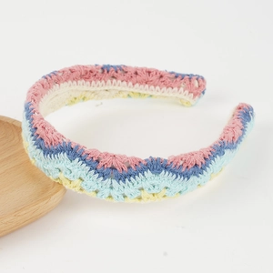 Detail eines bunten Boho-Haarreifs mit handgestricktem Wellenmuster und Häkelblumen-Design