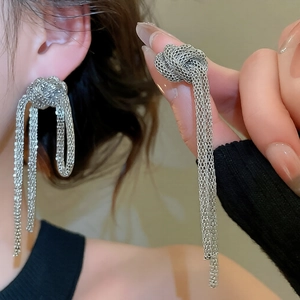 Retro silver chain knot tassel earrings worn by a model in a warm home setting