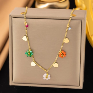 Goldene Kette mit bunten Blumenanhängern und Herzen auf einer Schmuckschatulle