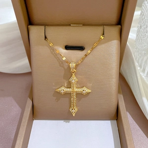 Close-up of a gold cross pendant necklace with sparkling rhinestones in a gift box