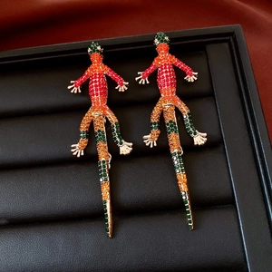 Dettaglio di orecchini vintage a forma di geco con strass multicolore in una scatola regalo