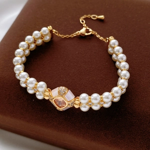 Détail d'un bracelet de perles plaqué or avec pierre rose et pavage en zircone