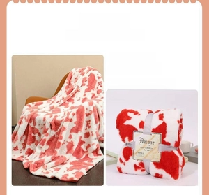 Detail of red and white cow print flannel blanket showing plush texture and packaging