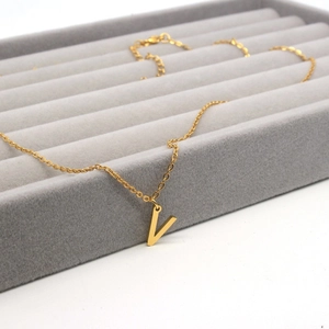 Close-up of golden V-shaped pendant necklace on a premium grey jewelry tray