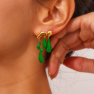 Detailed close-up of 18K gold plated asymmetric lava earrings with vibrant green enamel drip
