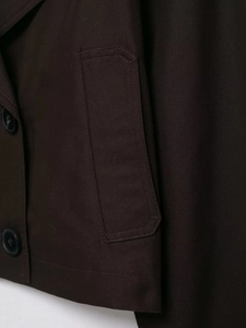 Detailed macro view of dark brown cropped trench coat featuring twill fabric and black buttons