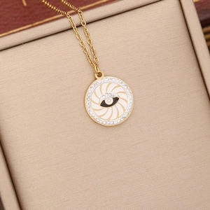 Detail of gold evil eye pendant with white enamel and crystals in a textured box