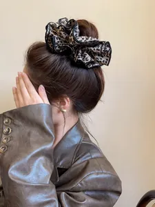 Dettaglio di scrunchie leopardato con bordi ondulati neri su un'acconciatura a coda di cavallo