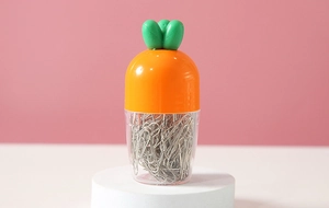 Macro shot of a carrot-shaped paperclip holder with metal clips on a white display stand