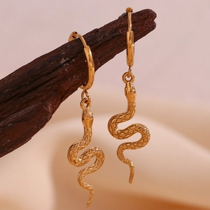 Detail of gold snake-shaped earrings hanging on a branch with hammered texture