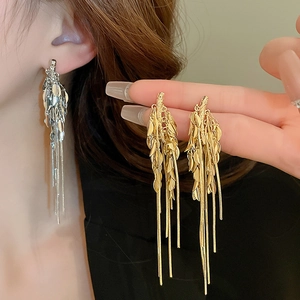 Detail showing long metal tassel earrings in gold and silver wheat ear leaf design